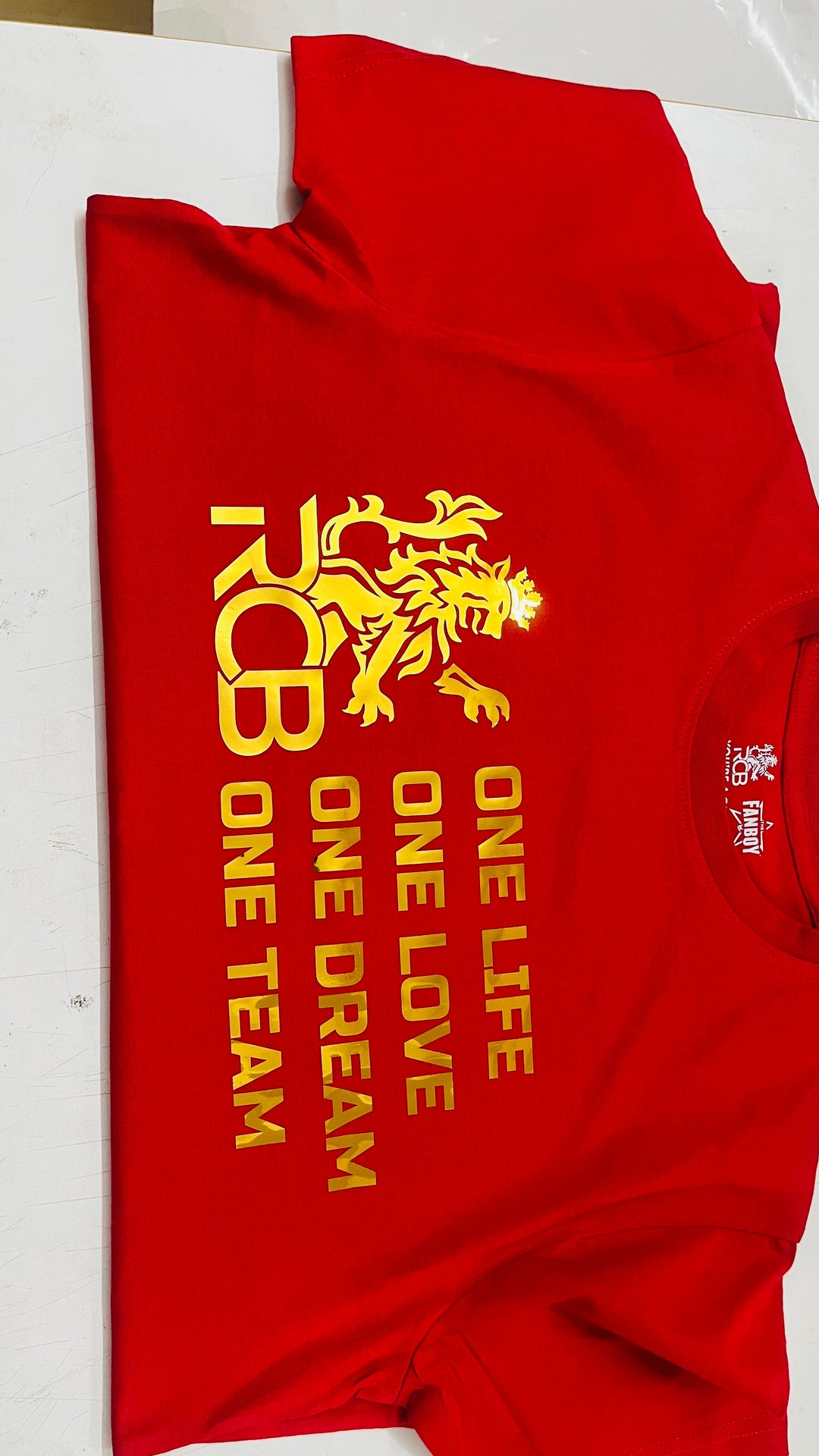 Premium RCB red and gold fan T-shirt featuring bold slogan and metallic print finish
