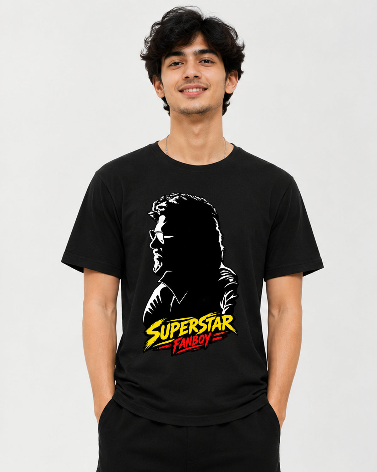 A man wearing a black short-sleeve t-shirt with a graphic print of a silhouette profile and the text 'SUPERSTAR FANBOY' in yellow, white, and red, against a light gray background.